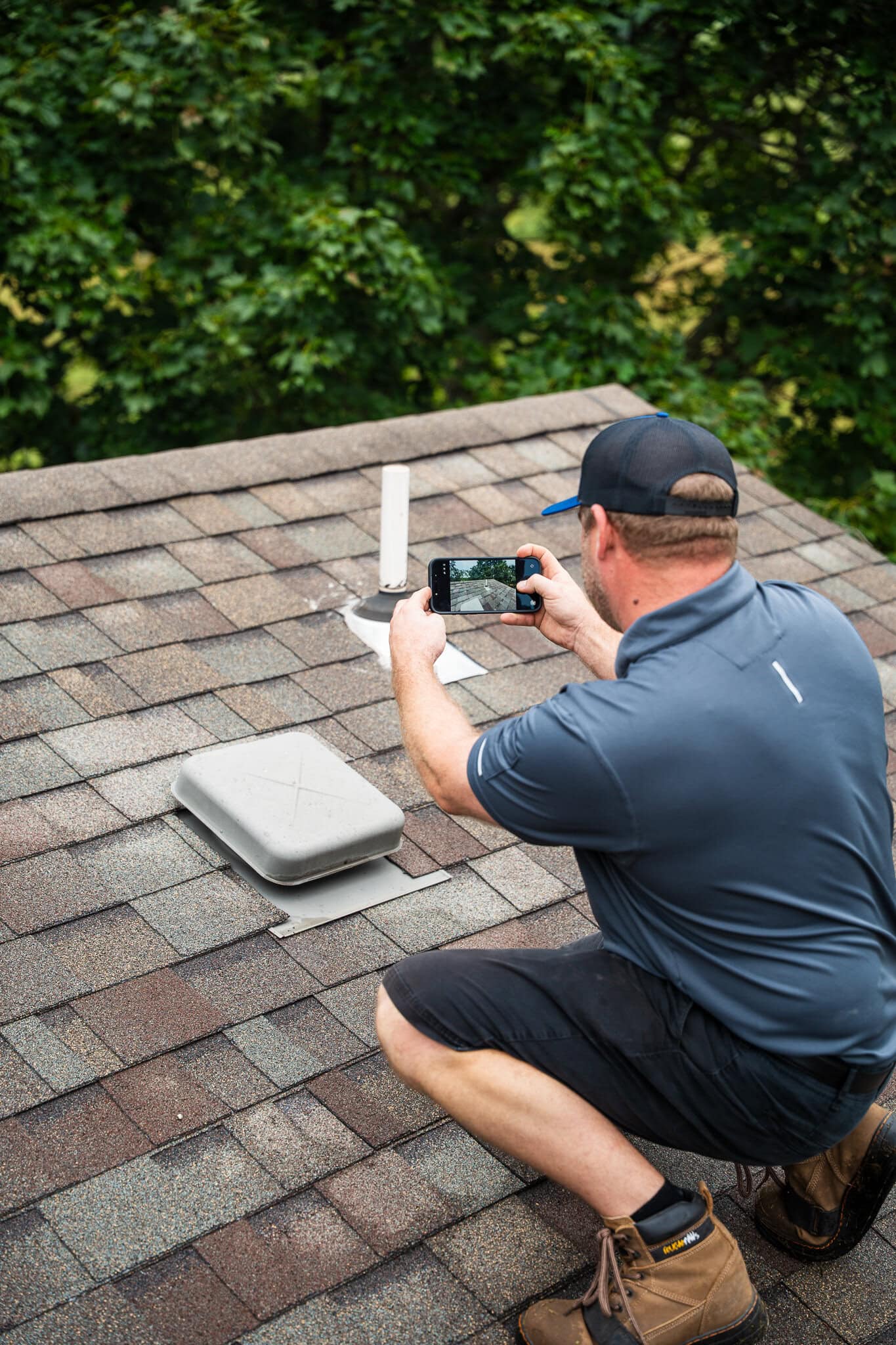 Man inspecting roof shingles for damage or wear on residential roof.