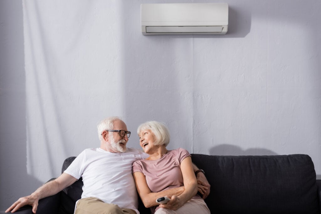 Efficient hvac unit cooling a cozy living room with elderly couple enjoying comfort, showcasing top-rated hvac and plumbing services by my jockey.