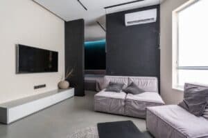 MODERN LIVING ROOM WITH HVAC UNIT, SLEEK TV, AND CONTEMPORARY FURNITURE, SHOWCASING TOP-RATED HVAC AND PLUMBING SERVICES FOR HOME COMFORT AND AIR QUALITY.