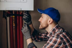 EFFICIENT HVAC TECHNICIAN INSPECTING PLUMBING AND HEATING SYSTEM, EMPHASIZING TOP-RATED HVAC AND PLUMBING SERVICES FOR HOME COMFORT AND REPAIR.