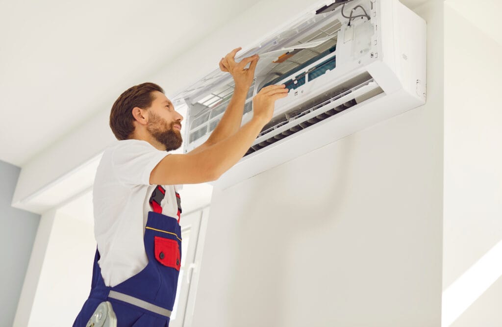 HVAC TECHNICIAN SERVICING A WALL-MOUNTED AIR CONDITIONING UNIT, EMPHASIZING PROFESSIONAL HVAC REPAIR SERVICES AND MAINTENANCE.