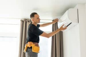 EFFICIENT HVAC TECHNICIAN INSTALLING OR REPAIRING AIR CONDITIONING UNIT FOR OPTIMAL HOME CLIMATE CONTROL, EMPHASIZING TOP-RATED HVAC SERVICES.