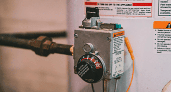 Close-up of a water heater control panel—temperature dial, warning labels, and pipes—showcasing the adjustment knob and caution stickers. Trusted plumbers in Warren MI, like Bison Plumbing, ensure every detail is safe and efficient.