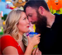 A couple sharing a romantic moment at a festive event, holding colorful drinks and smiling, showcasing professional holiday photography and love-themed portrait sessions.
