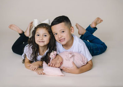 Adorable siblings newborn photoshoot with young girl and boy lying on studio floor, capturing family love and childhood moments, professional photographer, My Roots Photography Co.