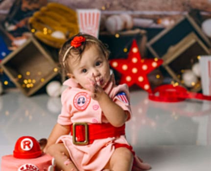 Adorable baby girl dressed in a pink costume in a festive holiday photoshoot, surrounded by Christmas decorations and themed props, capturing joyful childhood moments.