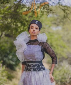 Robe longue, en pagne tissé couleur argentée, à brillantine argent, mix tulles brillant argent et dentelles noires. Avec ceinture large brodée et froufrous. Foulard et chapeau brodé assortis.