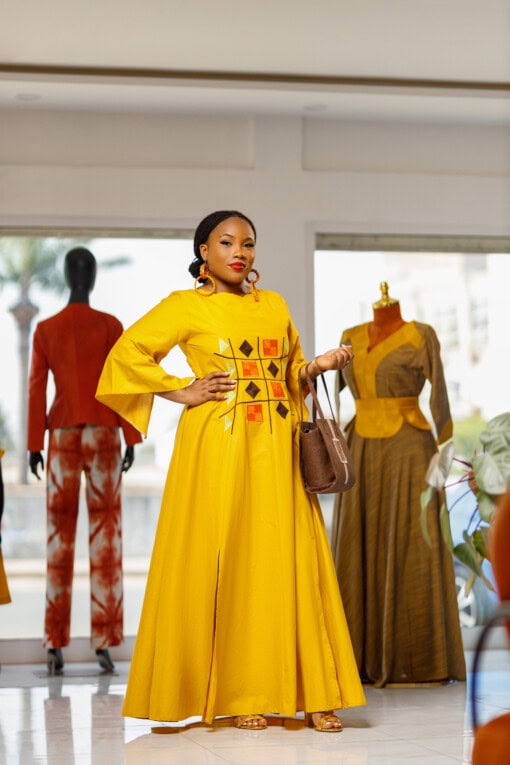 Longue robe brodé de couleur jaune moutarde avec manches 3/4 en tissu coton woodin avec des broderies à l'avant. La robe est agrémentée de fentes en bas sur chaque coté de la robe