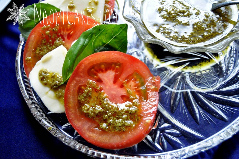 a tomato slice with pesto dressing on top with a blue tablecloth background