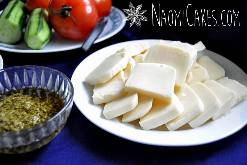 thick slices of soft mozzerella cheese with vegetables in the background