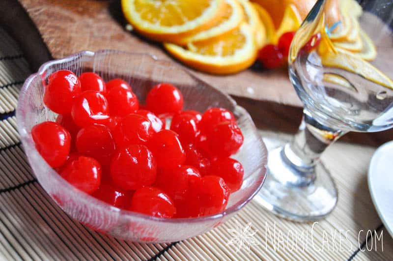 maraschino cherries in a bowl with sliced oranges in the background