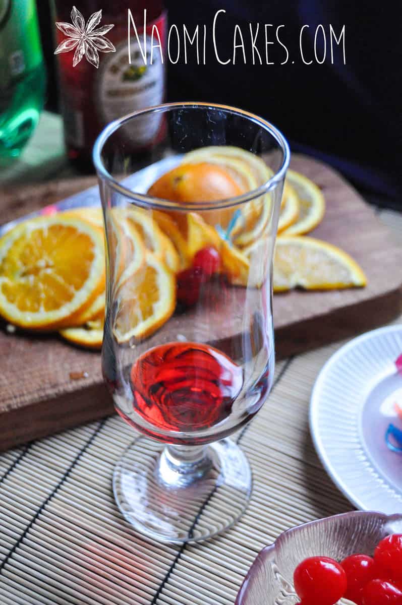 glass with cherry grenadine and mocktail garnishes in the background