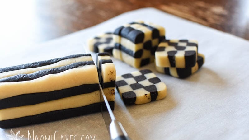 slicing checkerboard cookies from a square log of dough on parchment paper