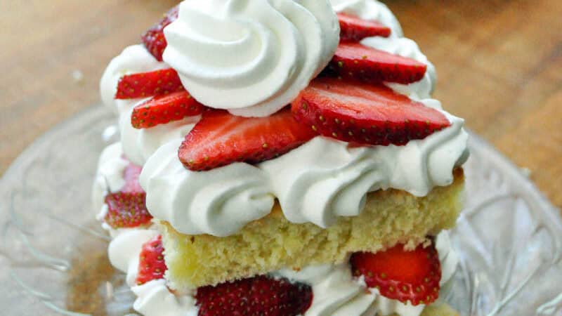 a square mini strawberry shortcake on a glass plate on a cutting board