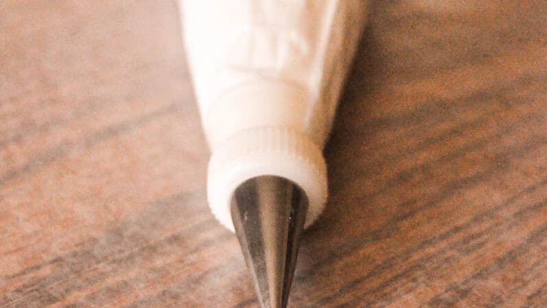 bag of white buttercream with a round tip on a wooden table