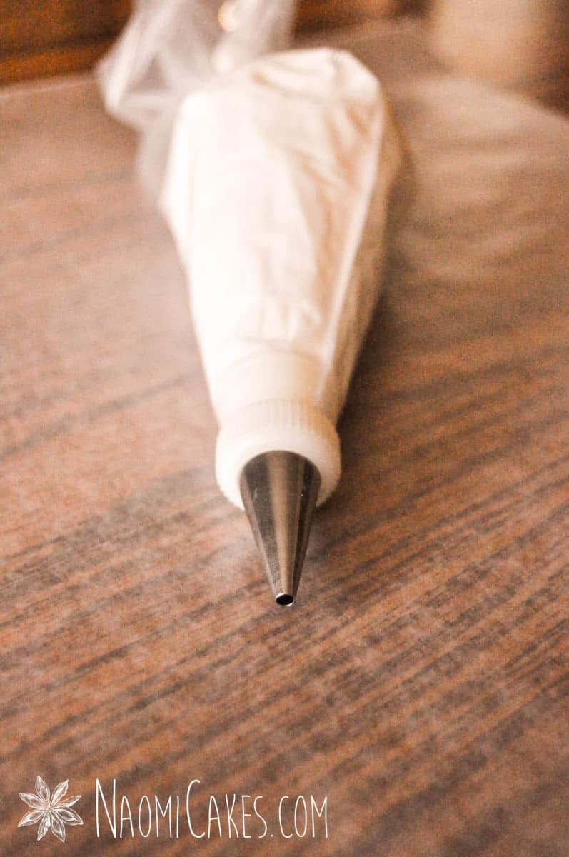 bag of white buttercream with a round tip on a wooden table