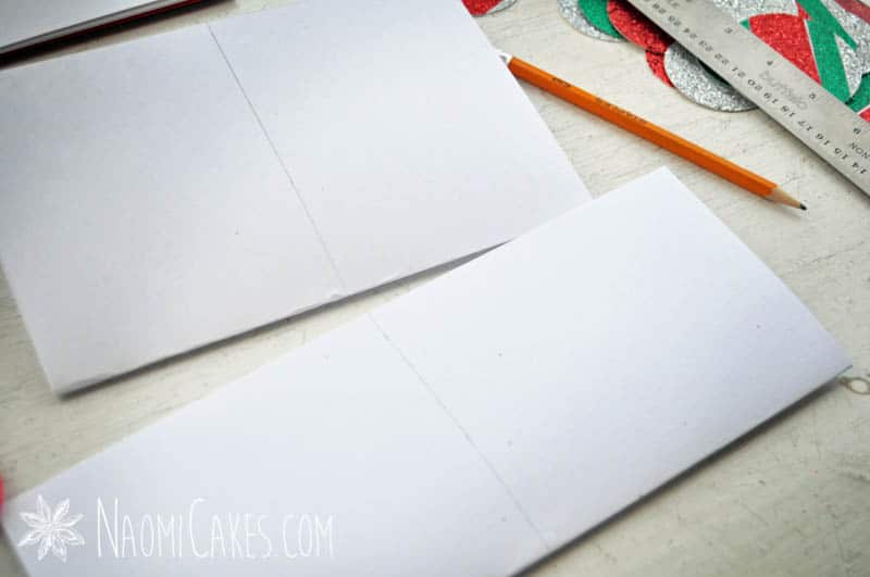 two sheets of white paper, folded and marked down the middle with pencil