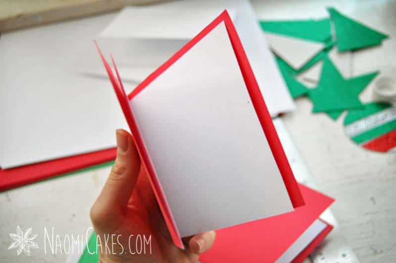 a hand holding a red homemade Christmas card with a white insert