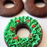 green piped leaves and red piped berries on a wreath shaped gingerbread cookie