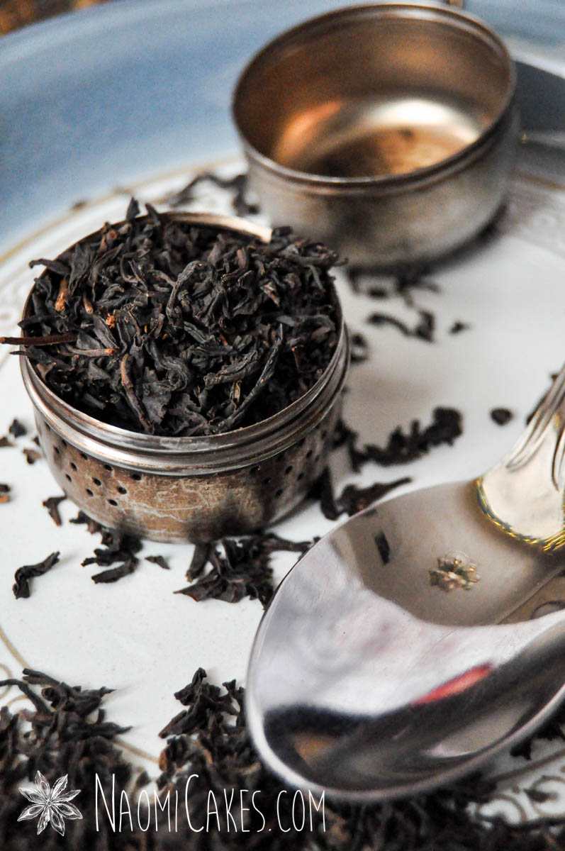 tea ball filled with black tea leaves on a blue plate