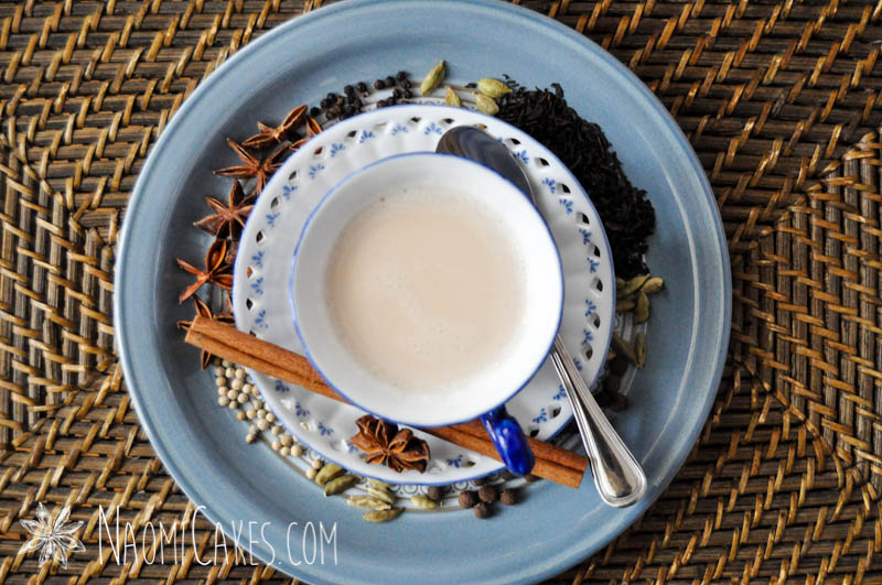 overhead view of chai tea with spices on a blue plate and basket tray