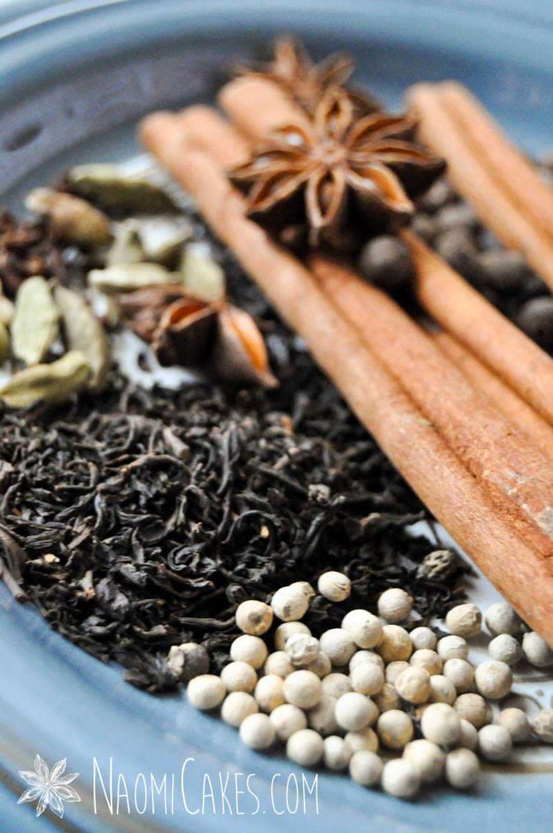 star anise, cinnamon sticks and other whole chai spices and tea on a blue plate
