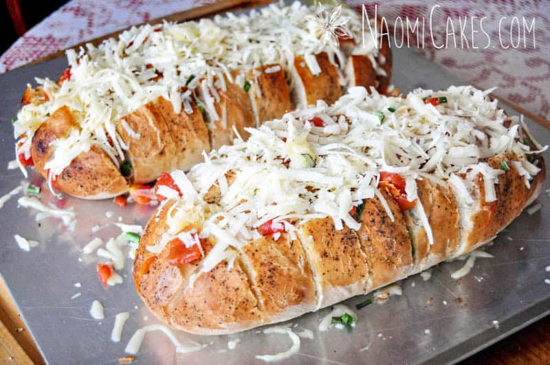 shredded cheese piled on garlic bread, ready to go in the oven