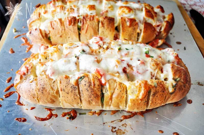 2 loaves of fresh cheesy garlic bread on a pan