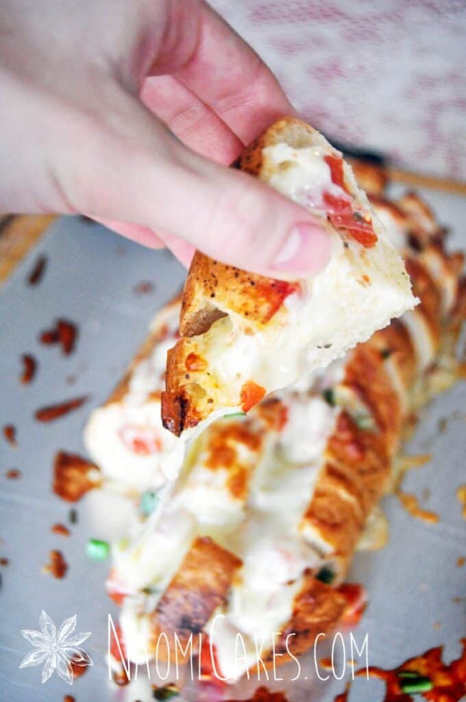 hand holding a piece of cheesy stuffed garlic bread