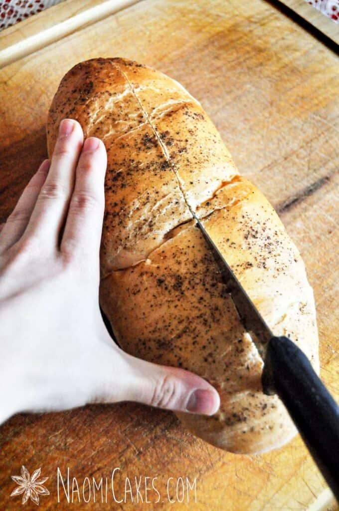 a girl's hands cutting a loaf of bread down the middle