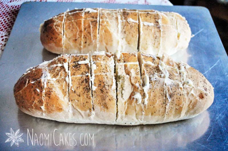 loaves of scored bread with garlic butter spread between the cuts