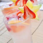 pink punch in two glass cups with star fruit and red strawberries