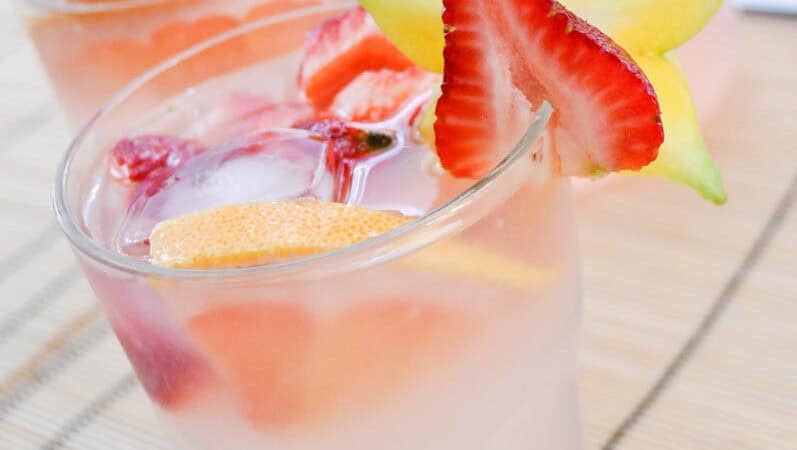 pink punch in two glass cups with star fruit and red strawberries