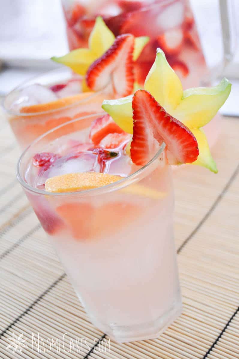 pink punch in two glass cups with star fruit and red strawberries