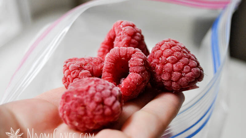 hand holding 5 frozen raspberries