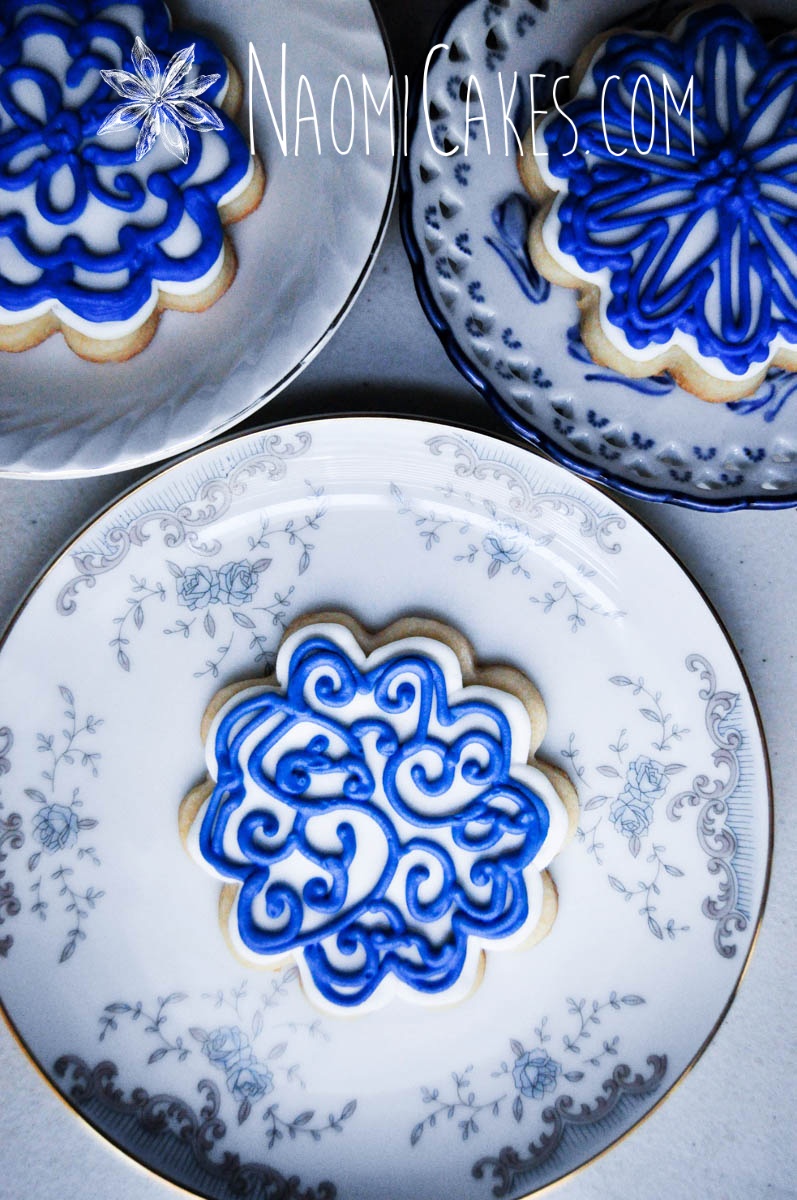 blue filigree design flower shaped sugar cookies on blue and white teacup saucers