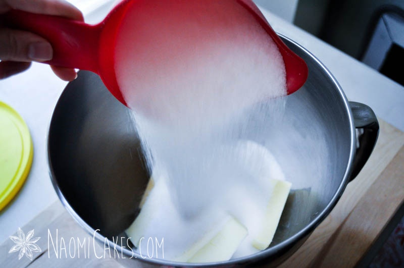 sugar pouring into a bowl with a red scoop