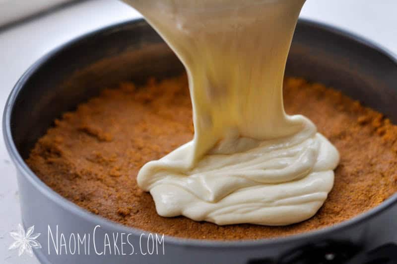 cheesecake batter pouring over the crust into a springform pan