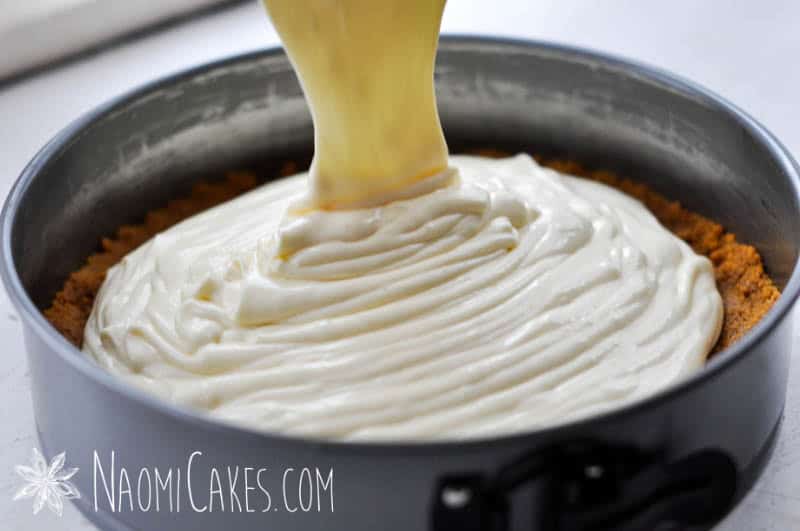 ribbons of cheesecake batter pouring over the crust into a springform pan