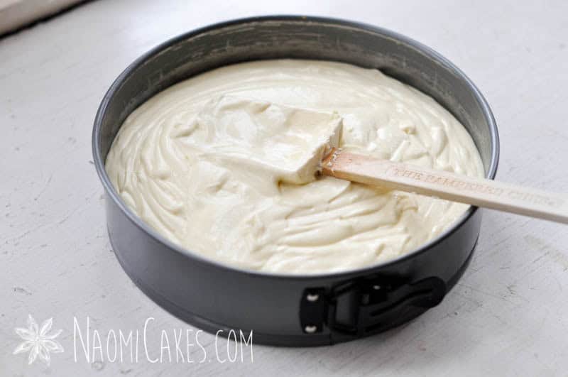 springform pan with a spatula sitting on top of cheesecake batter inside