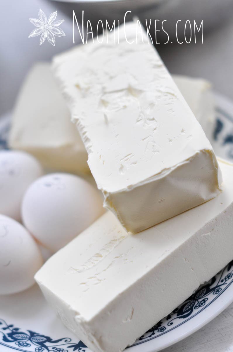 close up of 3 bricks cream cheese with eggs in the background