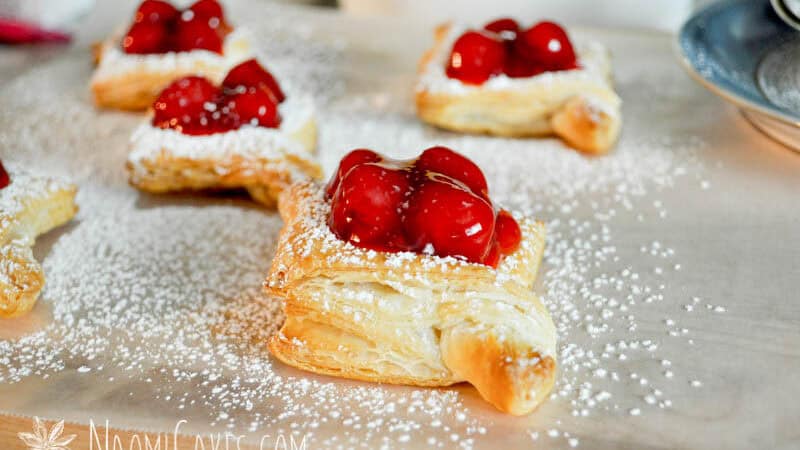 baked puff pastry diamonds with cherry pie filling and icing sugar