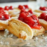 glass plate of baked puff pastry diamonds with cherry pie filling and icing sugar