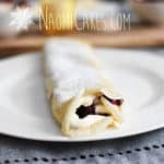 crepe on a white plate on a grey placemat with powdered sugar on top