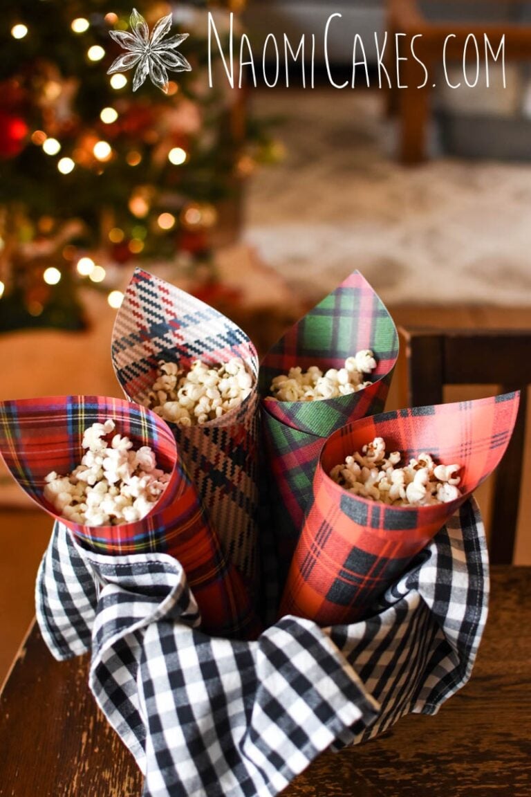 plaid Christmas paper cones filled with popcorn in front of Christmas lights