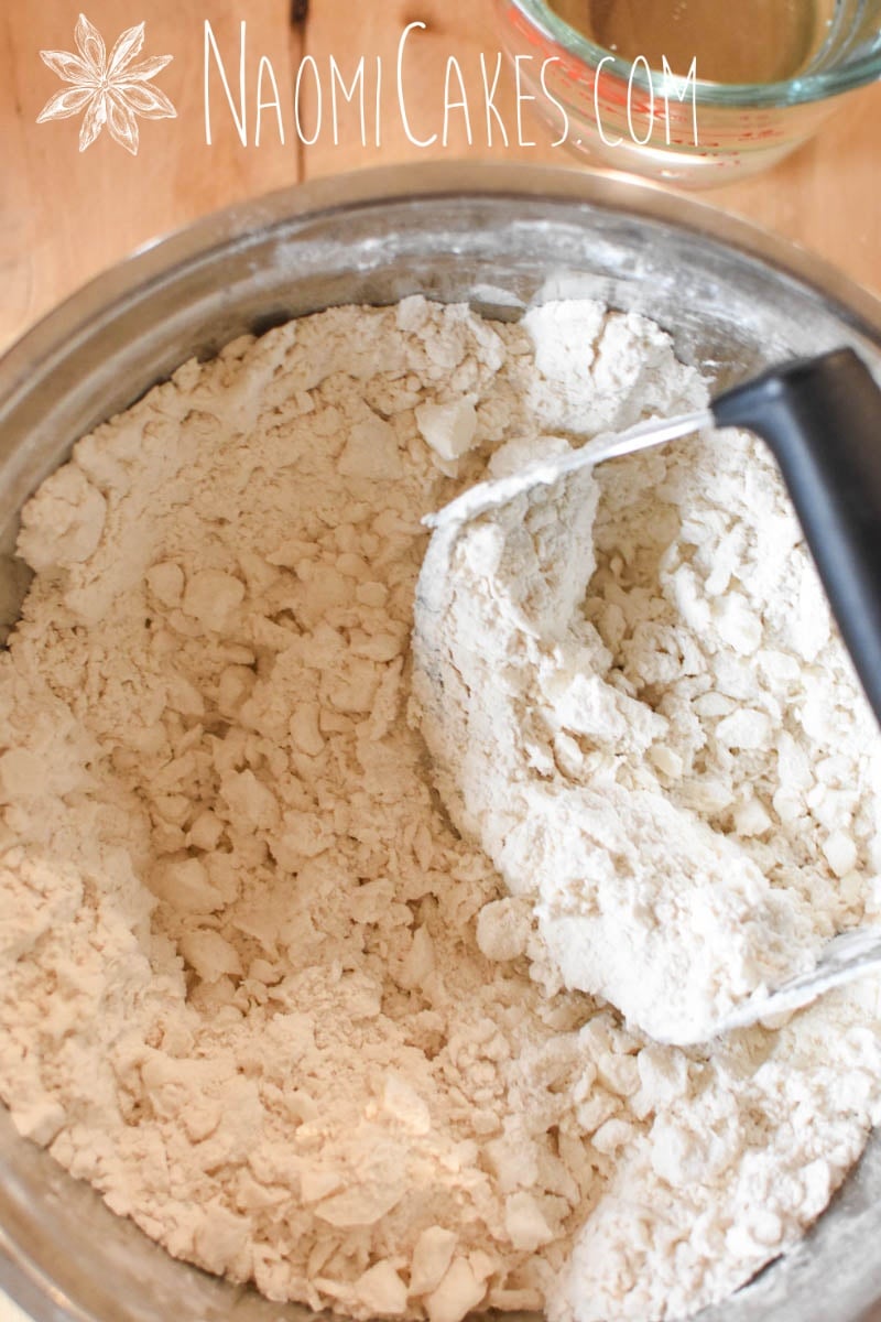 pastry cutter with shortening cut into flour in a metal bowl