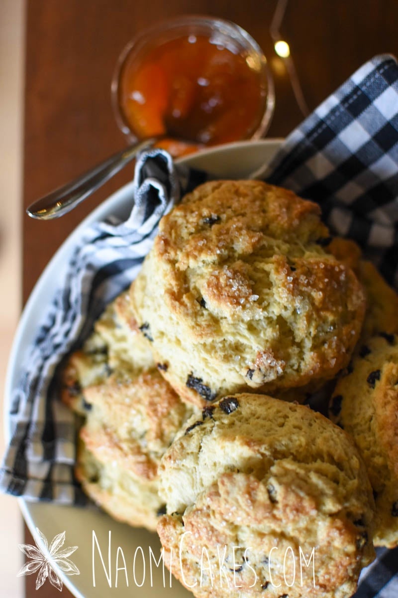 close up of large currant scones with apricot jam and fairy lights