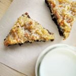 two German chocolate brownies cut into triangles with a glass of milk on parchment paper