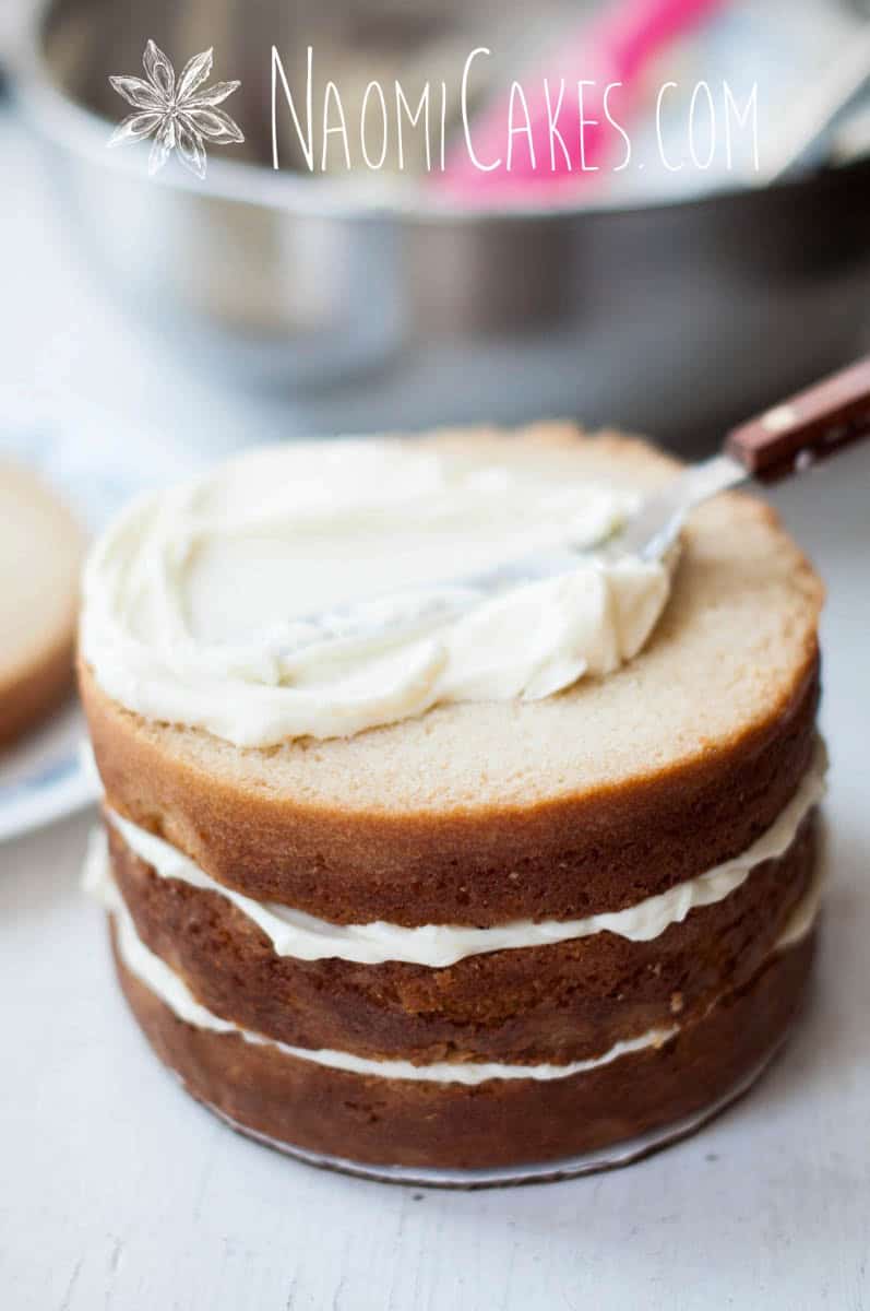 frosting being spread on a 4 layer vanilla cake