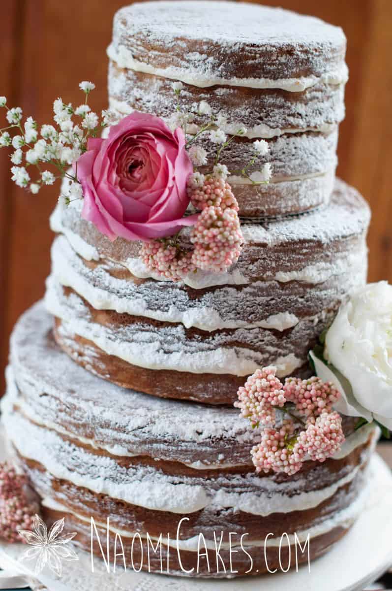 close up image of a 3 tier naked cake wedding cake with pink flowers